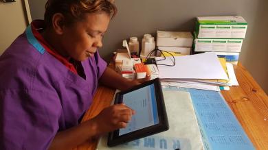 Eine Hebamme in einem Gesundheitszentrum in Antananarivo betrachtet die Daten, der am Tag behandelten Patientinnen. Schwangere können in diesem Gesundheitszentrum mit dem Handy bezahlen.