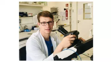 Timo Uphaus in front of a surgical microscope