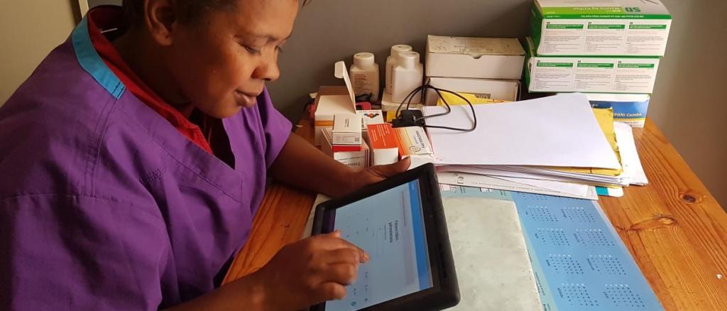 Eine Hebamme in einem Gesundheitszentrum in Antananarivo betrachtet die Daten, der am Tag behandelten Patientinnen. Schwangere können in diesem Gesundheitszentrum mit dem Handy bezahlen.
